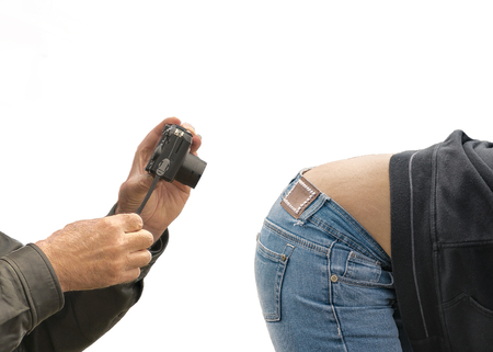 Funny photo montage of old man taking photos of crouching young woman wearing jeans against white backgroundの写真素材