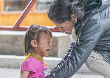 ALAUSI, ECUADOR, OCTOBER - 2015 - Closeup photo of young mother comforting her daughter crying.のeditorial素材