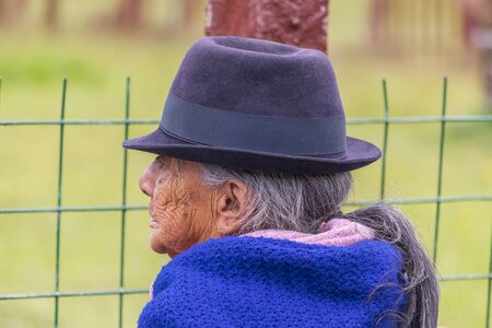 AZUAY, ECUADOR, OCTOBER - 2015 - Side view portrait of indigenous old woman with hat against blurry background.のeditorial素材