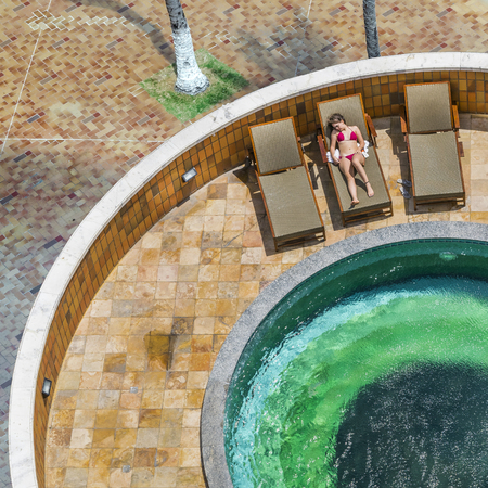 FORTALEZA, BRAZIL, DECEMBER - 2015 -  Top view of attractive young woman with red swimsuit sunbathing at hotel swimming poolのeditorial素材
