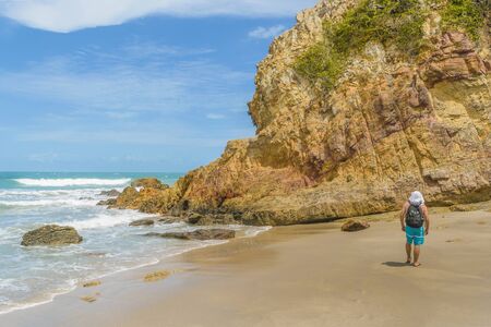 Man with backpack at rocky beach in Praia Malhada, Jericoacoara, Brazilの写真素材