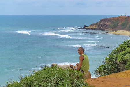 TIBAU DO SUL, BRAZIL, JANAURY - 2016 - Old man with hi dog at landscape scene of coast at Tibau do Sul, a watering place located in Brazilのeditorial素材