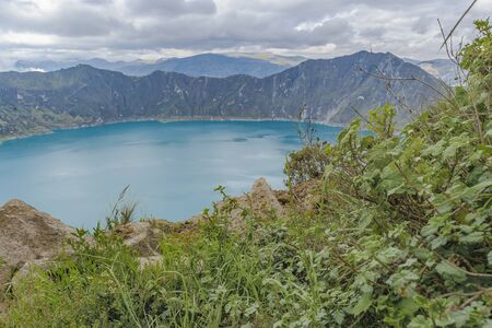 Quilotoa lake and andes range mountain against overcast cloudy background landscape scene, Ecuadorの写真素材