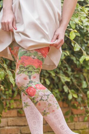 Woman legs detail with floral printed leggings and black shoes at outdoor yard backgroundの写真素材