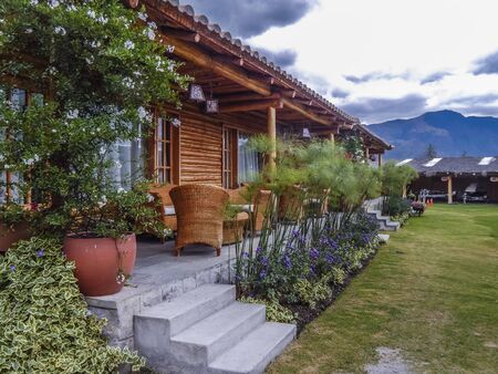 Touristic rustic style wood house with garden decoration and mountains and cloudy sky at background at San Pablo lake, Imbabura, Ecuadorのeditorial素材