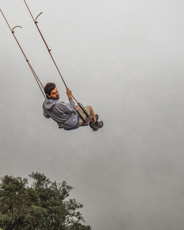 BANOS, ECUADOR, OCTOBER - 2015 - Young man swinging at casa del arbol, Banos, Ecuador