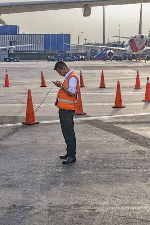 LIMA, PERU, APRIL - 2016 - Worker watching his cellphone at Jorge Chavez airport runway in Lima city, Peruのeditorial素材