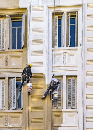 MONTEVIDEO, URUGUAY, JUNE - 2017 - Two workers hanging by cables painting the facade of apartment building in Montevideo, Uruguayのeditorial素材