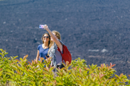 GALAPAGOS, ECUADOR, AUGUST - 2016 - Attractive young women taking a selfie at sierra negra volcano, the second largest volcano on earth, located in Isabela island, Galapagos, Ecuadorのeditorial素材