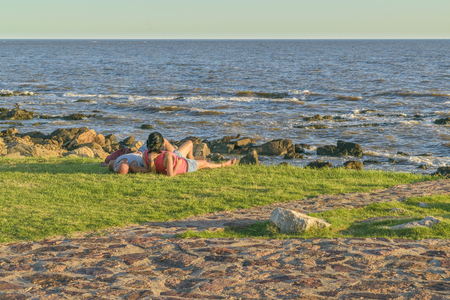 MONTEVIDEO, URUGUAY, FEBRUARY - 2016 - Couple resting at grass at coast of river in Montevideo city, Uruguayのeditorial素材