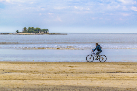 MONTEVIDEO, URUGUAY, JULY - 2016 - Man riding a bicycle at malvin beach in the coast of Montevideo city, Uruguayのeditorial素材