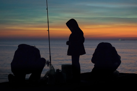 High contrast photo of group of people fishing at breakwater at coast of river in Montevideo city, Uruguayの写真素材