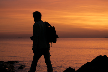 High contrast photo of man with backpack walking at coast of river in Montevideo city, Uruguayの写真素材