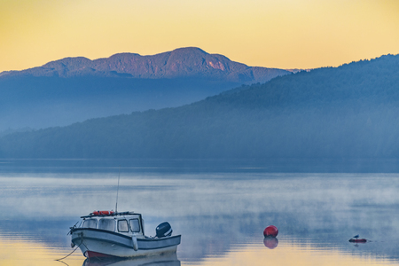 Small boat parked at lake at foggy morning at Puyuhuapi village, Aysen, Chileの写真素材