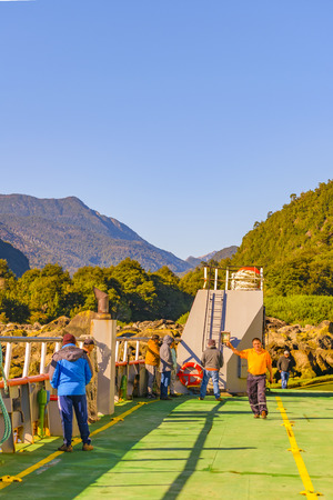 LOS LAGOS, CHILE, APRIL - 2017 - Workers at inside of ferry with landscape forest scene at background.のeditorial素材