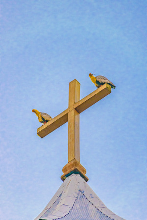 Low angle shot of two birds iver wooden church cross at Chiloe island, Chileの写真素材