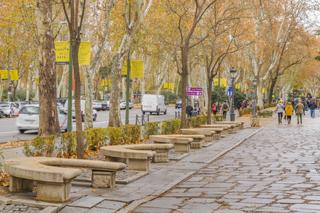 MADRID, SPAIN, DECEMBER - 2017 - People walking at cobblestone street at Paseo del prado sidewalk in...