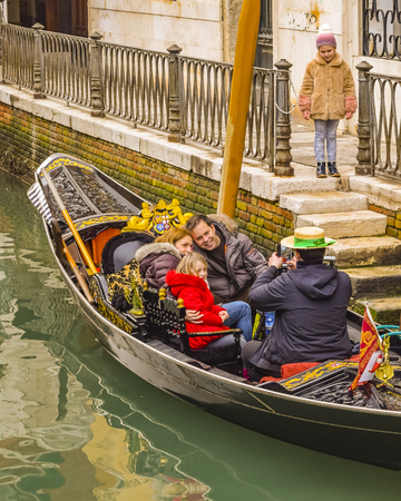 VENICE, ITALY, JANUARY - 2018 - Family being photographed by gongolier at venice channel, Italyのeditorial素材