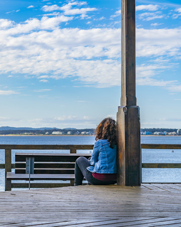 PUNTA DEL ESTE, URUGUAY, OCTOBER - 2018 - Woman watching the sea at waterfront boardwalk in punta del este city, Uruguayのeditorial素材