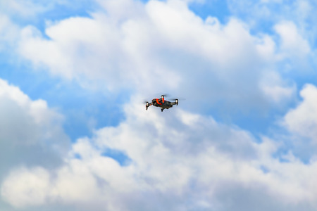 Small drone flying over cumulus sky background