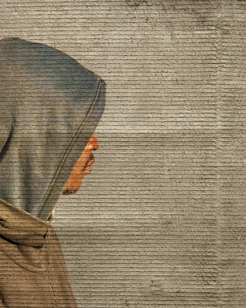 Side view shot black man with hood over grungy textured backgroundの写真素材