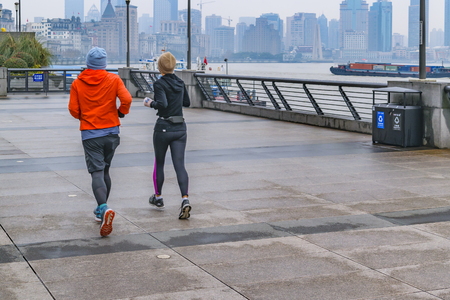 SHANGHAI, CHINA, DECEMBER - 2018 - Couple running at winter time at famous the bund zone in shanghai city, chinaのeditorial素材