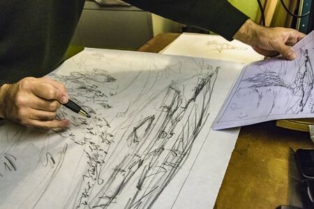 Interior scene of adult artist sketching his next artwork at workshop
