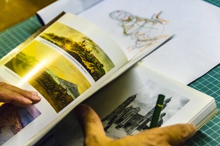 Interior scene of adult artist sketching his next artwork at workshop