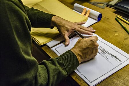Interior scene of adult artist sketching his next artwork at workshop