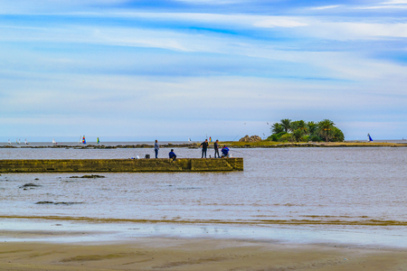MONTEVIDEO, URUGUAY, MAY - 2019 - Winter nature scene with people fishing at breakwater in malvin beach, montevideo, uruguayのeditorial素材