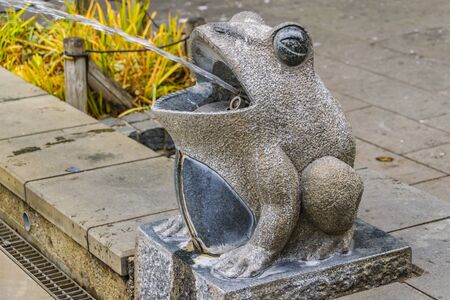 Curioos toad sculpture spitting water at foutain, ueno park, tokyo, japanの写真素材