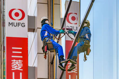 TOKYO, JAPAN, JANUARY - 2019 - Wokre cleaning window glasses of buildingsat shibuya district in...