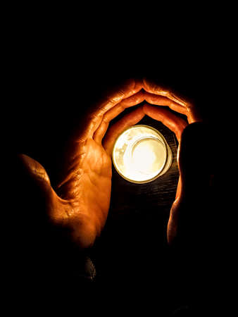 Man hands covering candle on glass over tableの写真素材