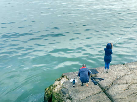 High angle shot young couple fishing at coast of river plate river, montevideo, uruguay