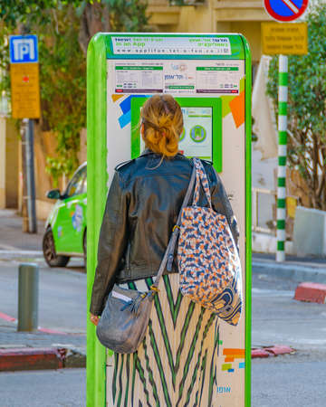 TEL AVIV, ISRAEL, DECEMBER - 2019 - Young woman using transportation machine ticket slot, rotschild pedestrian in tel aviv city, israelのeditorial素材