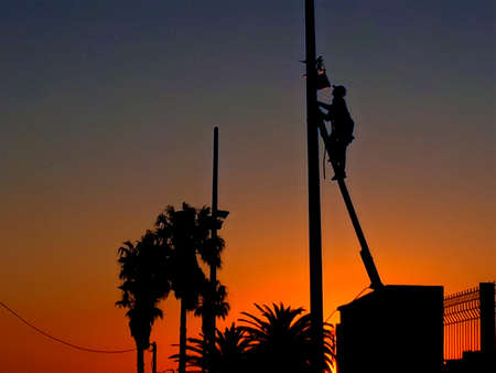 Worker checking urban electricity sunset silhouette sceneの写真素材