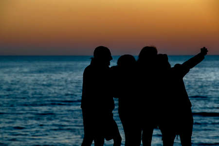 Sunset silhouette scene people at front of coast beach, canelones department, uruguayの写真素材