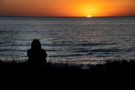 Back view person silhouette watching sunset, canelones department, uruguayの写真素材