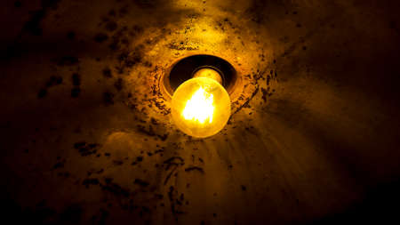 Low angle detail old rusty lamp illuminated by yellow bulbの写真素材