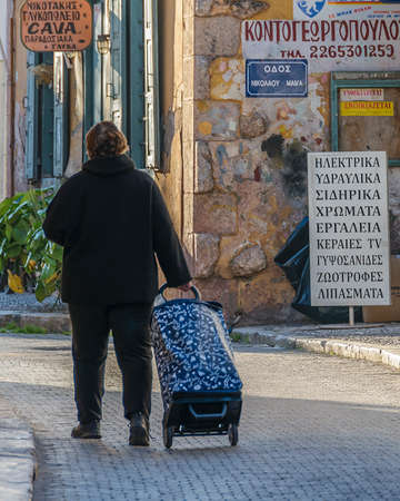 GALAXIDI, GREECE, JANUARY - 2020 - Old woman carrying bag at galaxidi street, phocis, greeceのeditorial素材