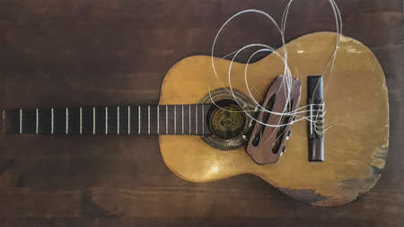 Top view broken spanish guitar over wooden tableの写真素材