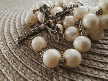 Rosary with crucifix over textured placemath close up shot