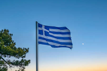 Greece flag over sunset sky backgroundの写真素材