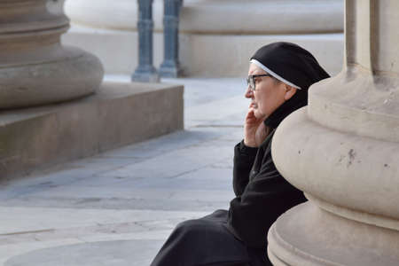 PARIS, FRANCE, JANUARY - 2020 - Nun with thinking expression sitting at side of column, Paris, Franceのeditorial素材