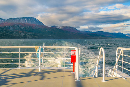 Back view excursion ship sailing through beagle channel with island mountains in background, ushuaia, argentinaの写真素材
