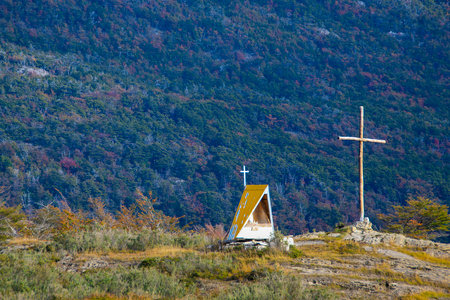 Small sanctuary at top of hill and in front of big andes mountains, ushuaia, tierra del fuego, argentinaの写真素材