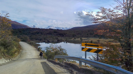 Man walking at dirt highway surrounded by Tierra del Fuego National Park landscape, Ushuaia, Argentinaのeditorial素材