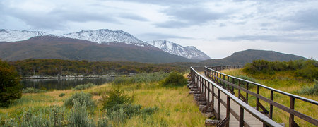 Empty wooden road and snowy Andes mountains at background, Tierra del Fuego National Park, Argentinaのeditorial素材