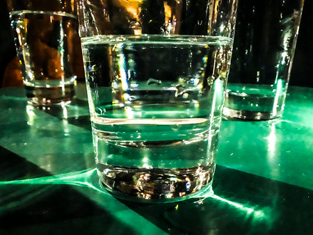 Night high contrast scene close up shot glasses with water at table at pub courtyard, Montevideo,...