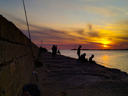People fishing at breakwater at sunset time, Ciudad Vieja, Montevideo City, Uruguayの写真素材